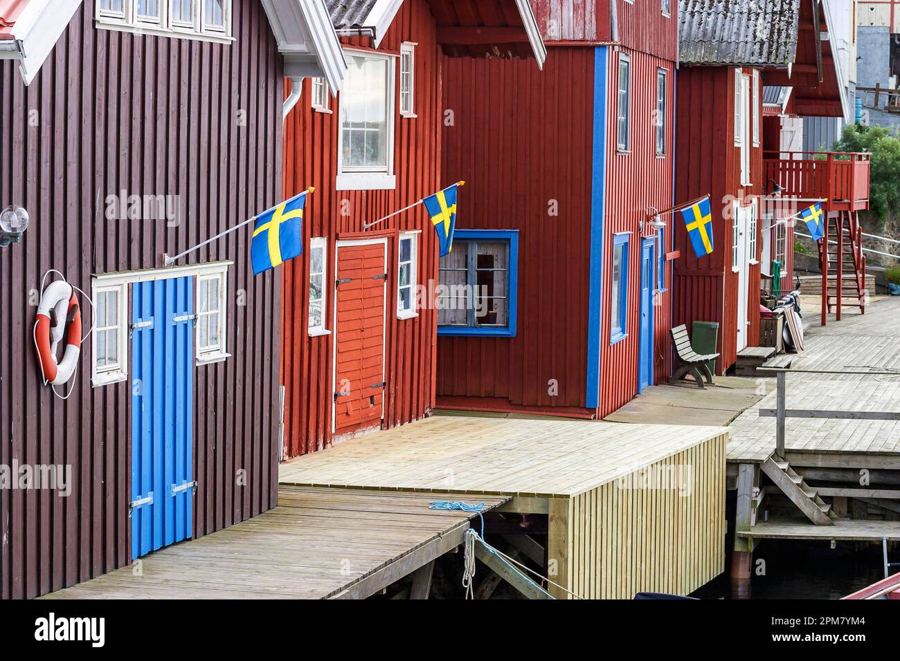 Boathouses idilliaco in un vecchio villaggio di pescatori e la bandiera svedese Foto Stock