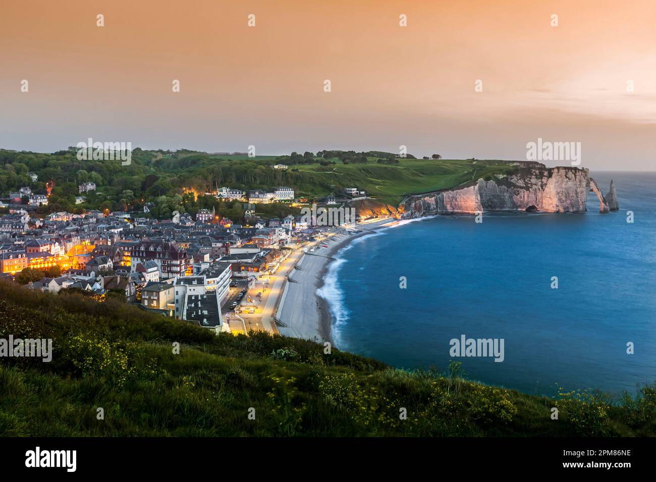 Francia, Seine-Maritime, Pays de Caux, Costa d'Alabastro (Cote d'Albatre), Etretat, vista elevata della città e scogliere illuminate, al tramonto Foto Stock