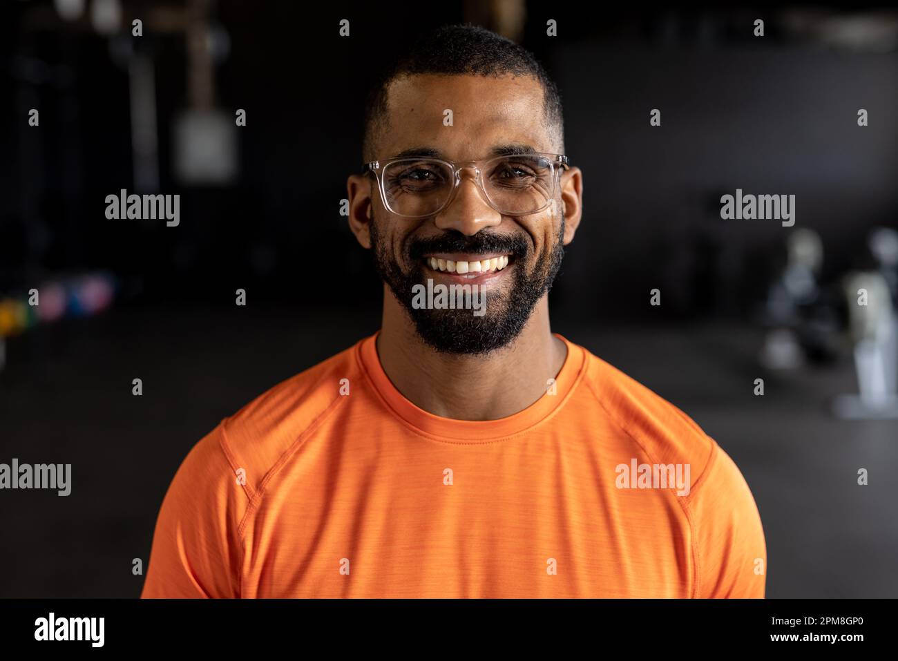 Ritratto di giovane biraciale sorridente portatore di occhiali in palestra Foto Stock