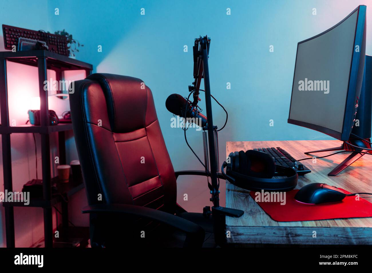 Una scrivania nera con un'ampia gamma di apparecchiature per giochi, come tastiere, controller e cuffie, perfettamente disposte sulla superficie Foto Stock
