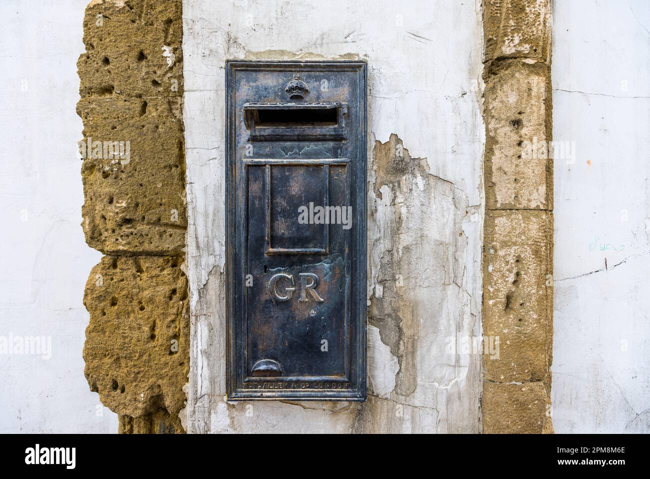 Una cassetta postale britannica montata a muro con il monogramma "GR" per Georgius Rex si trova in un muro di arenaria consumato nel centro storico di Lefkoşa/Nicosia, quartiere di Arabahmet, Repubblica Turca di Cipro del Nord (RTNC). Il monogramma si riferisce a re Giorgio V, che regnò dal 1910 al 1936 e durante il cui regno la cassetta postale fu installata. Foto Stock