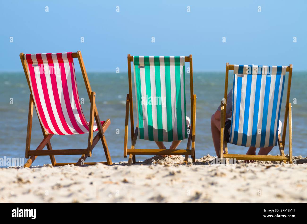 Tre sedie a sdraio colorate a righe su Una spiaggia di sabbia in Un giorno di sole, Avon Beach Christchurch UK Foto Stock