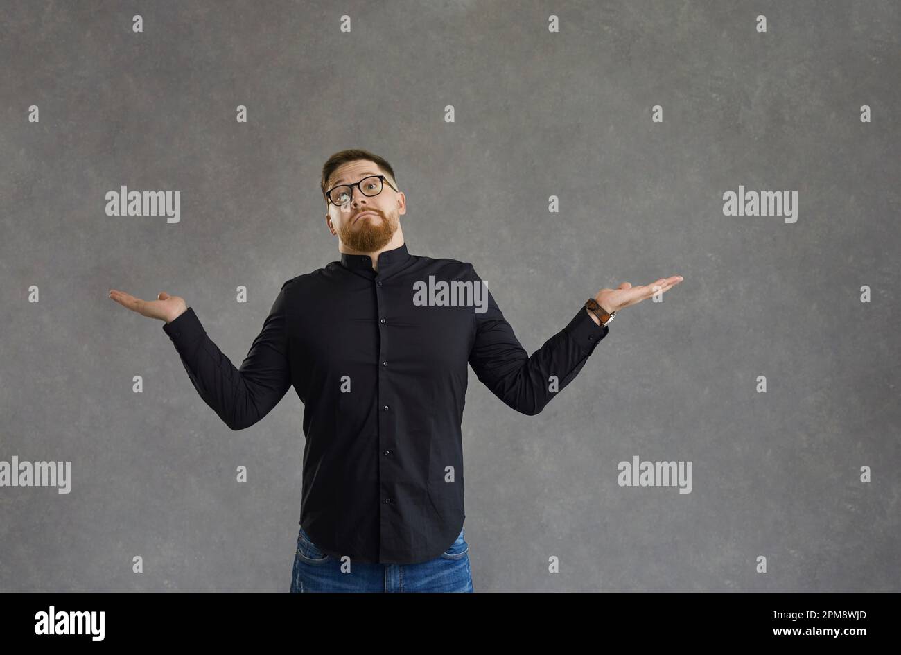 Confuso uomo perplesso con dubbio volto diffusione mani ampiamente in studio Foto Stock