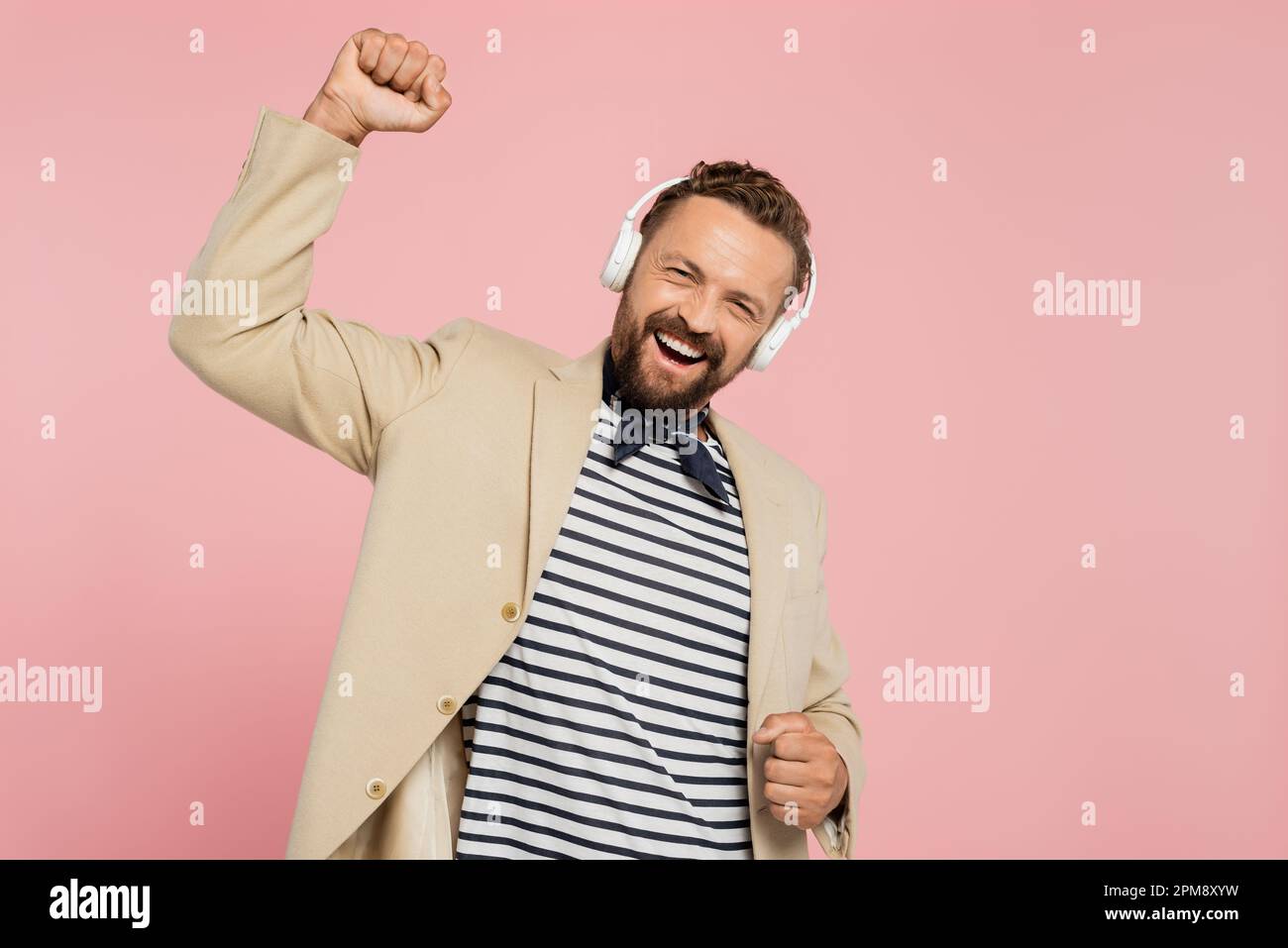 uomo francese eccitato in blazer e sciarpa collo ascoltare musica in cuffie  wireless isolato su rosa, immagine stock Foto stock - Alamy