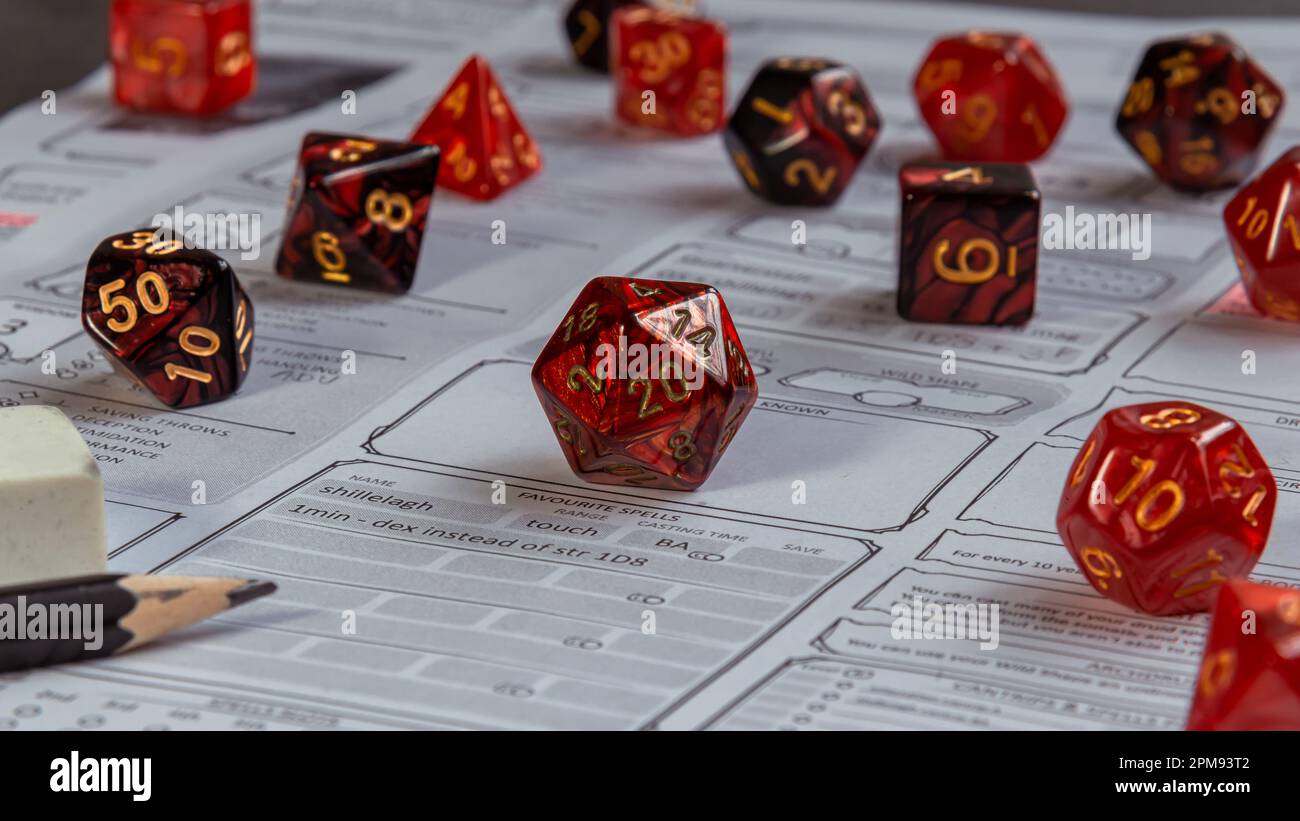 Immagine ravvicinata di un set di dadi rossi per giochi RPG su un foglio di un personaggio Foto Stock