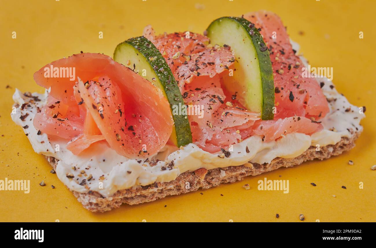 salmone con formaggio cremoso e cetriolo su cracker di segale e condito con pepe. Foto Stock