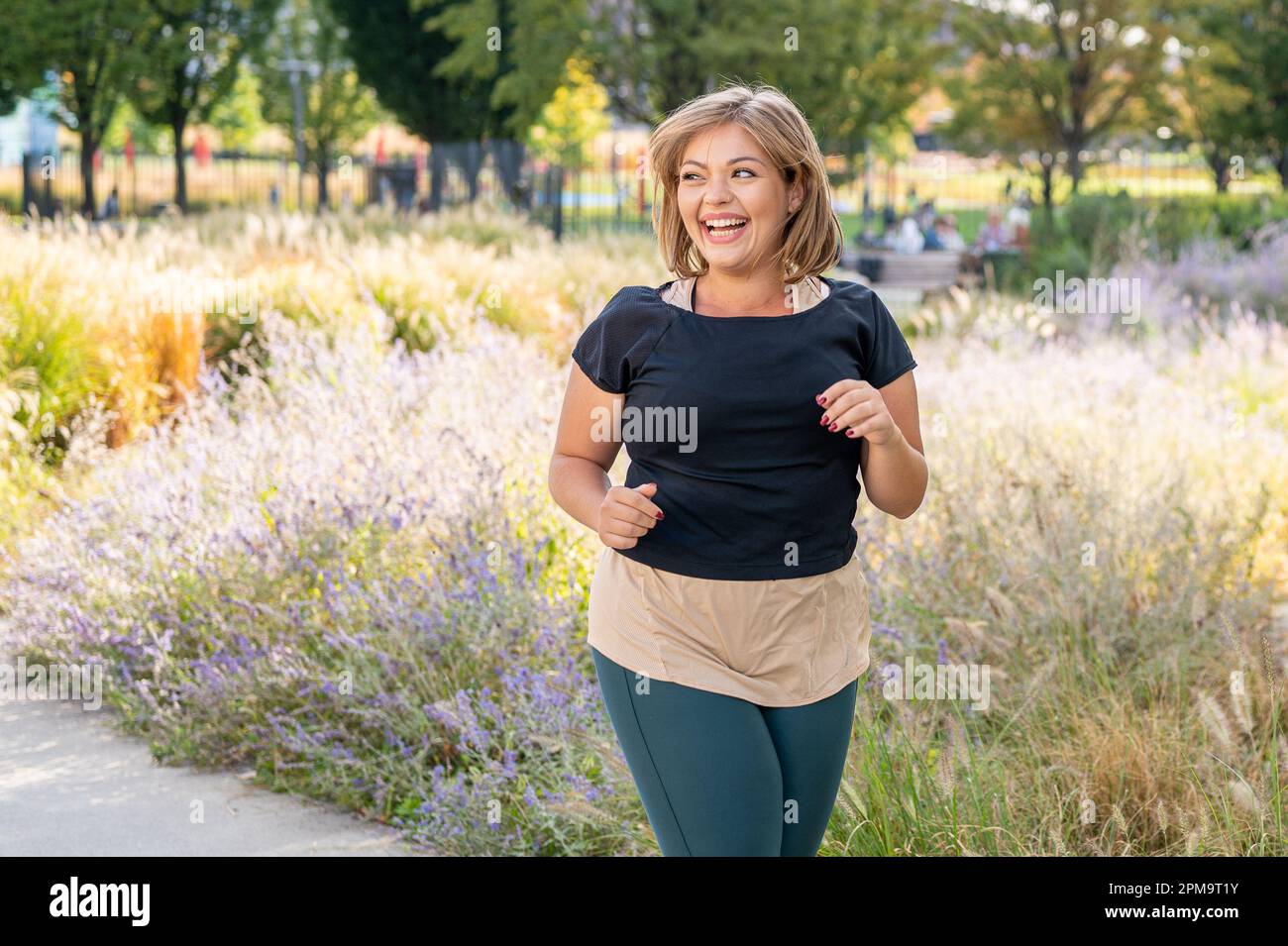 Felice e toothy sorriso donna jogging, donna sportiva in esecuzione all'aperto, corpo positivo e sano stile di vita concetto Foto Stock