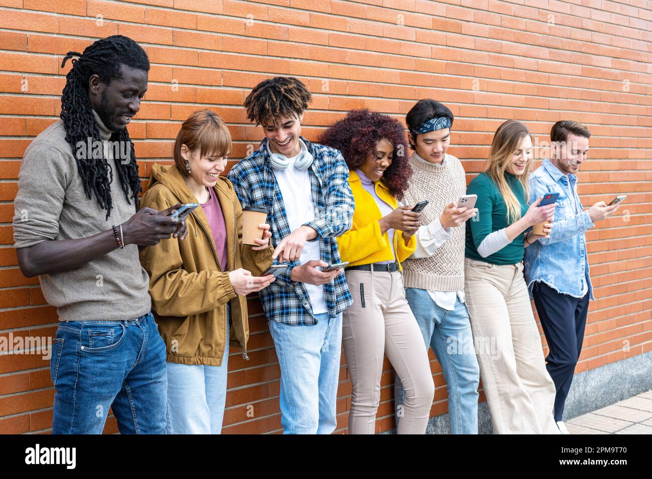 Giovani che guardano giù al telefono cellulare, adolescenti che si  appoggiano su un muro e che testano con i loro smartphone, concetti di  tecnologia e comunicazioni Foto stock - Alamy