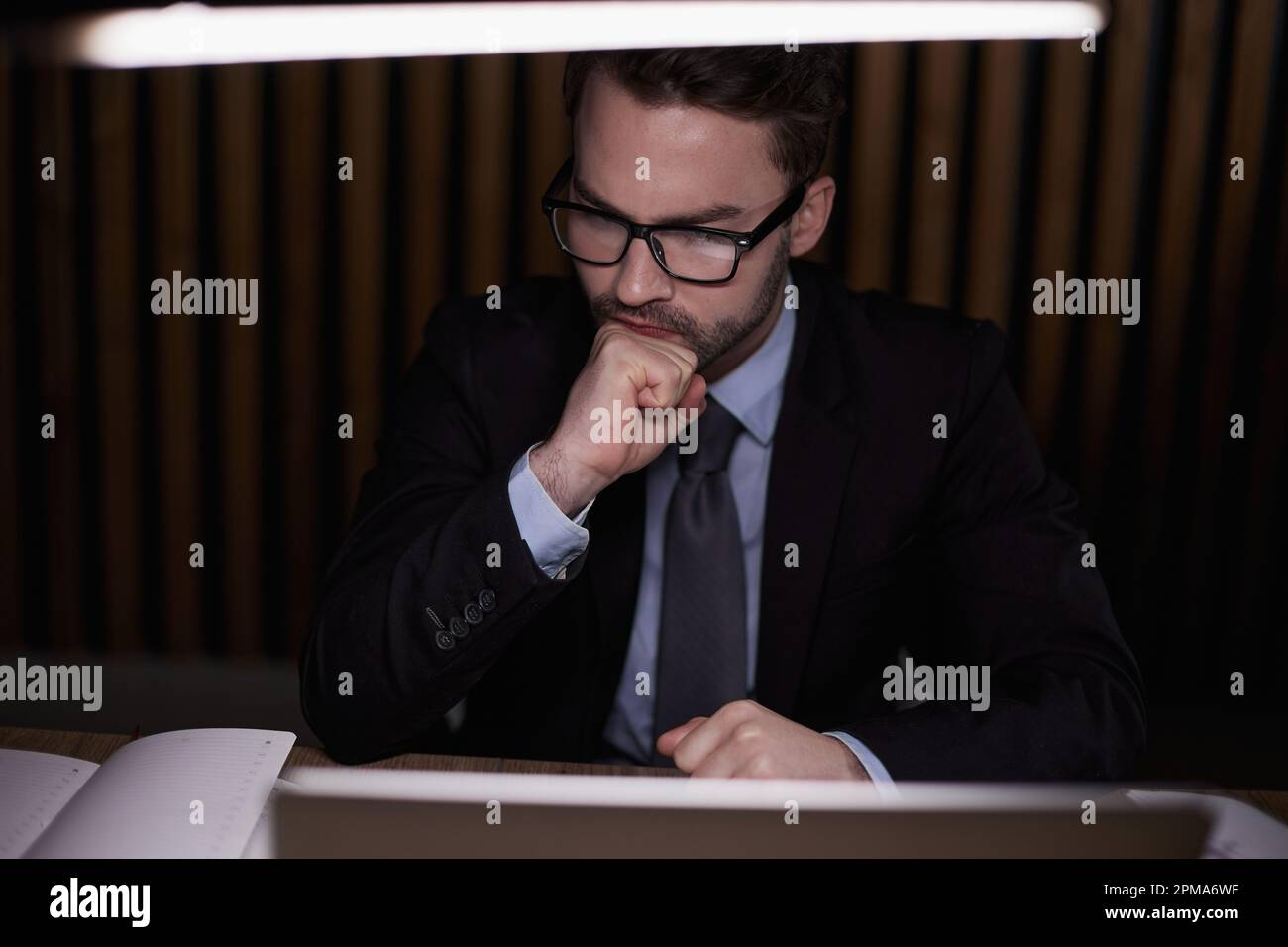 L'uomo sta pensando dietro al notebook. Foto Stock