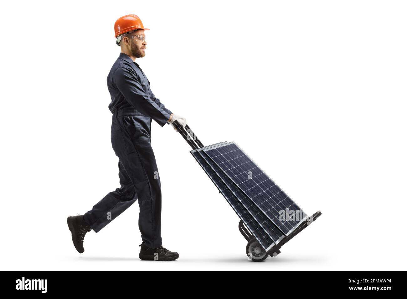 Foto a profilo completo di un operatore di fabbrica che spinge un camion a mano con pannelli solari isolati su sfondo bianco Foto Stock