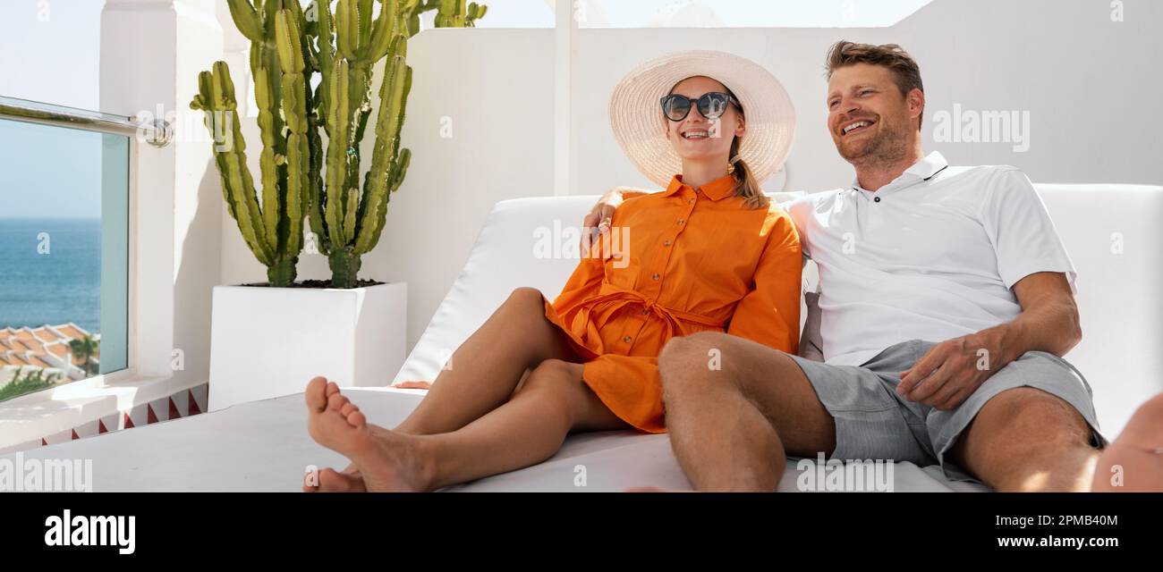vacanza romantica. coppia sorridente che si rilassa nel lettino insieme sulla terrazza dell'attico e che si gode le vacanze estive Foto Stock