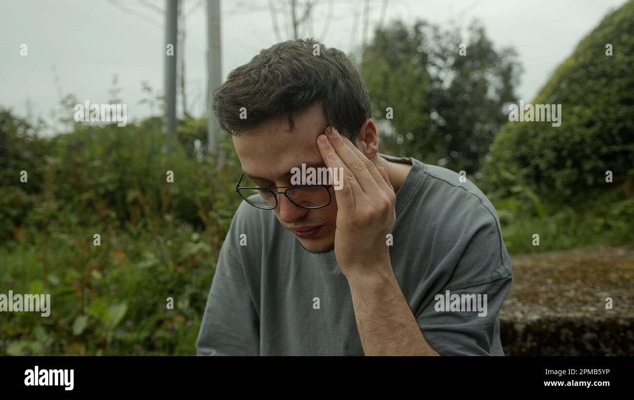 L'uomo con gli occhiali si batte nel dolore, combattendo un'improvvisa comparsa di problemi di salute Foto Stock