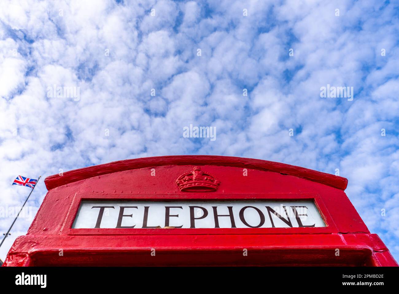 Londra chiama! Iconica cabina telefonica rossa britannica accanto al London Bridge a Lake Havasu City, Arizona, con bandiera britannica in soft focus sul retro Foto Stock