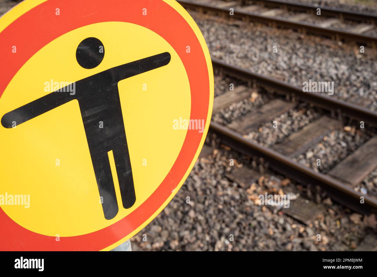 Cartello circolare senza passaggio sulla piattaforma ferroviaria con binari sullo sfondo Foto Stock