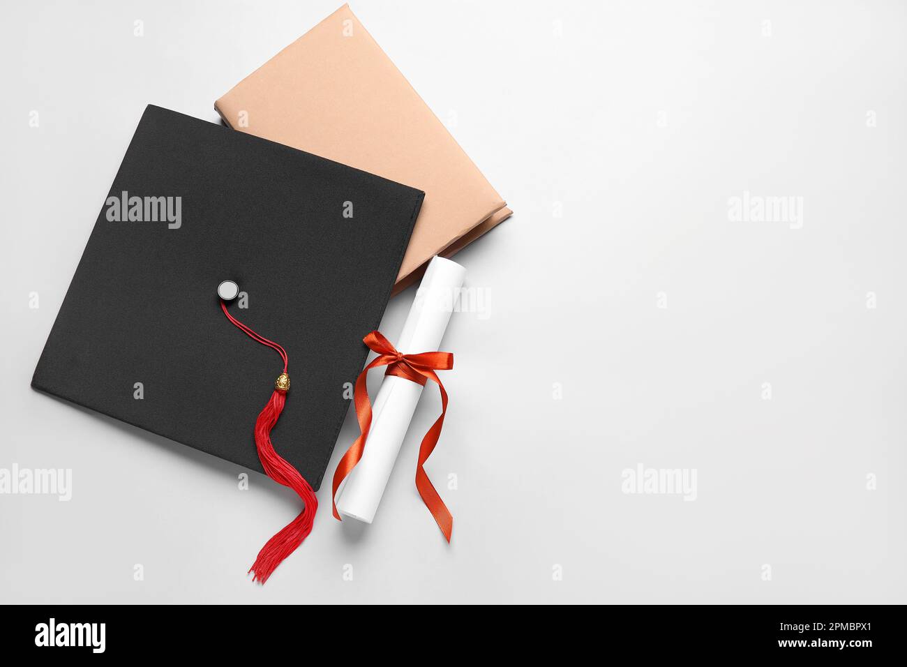 Diploma con nastro rosso, cappello di laurea e libro su sfondo bianco Foto Stock