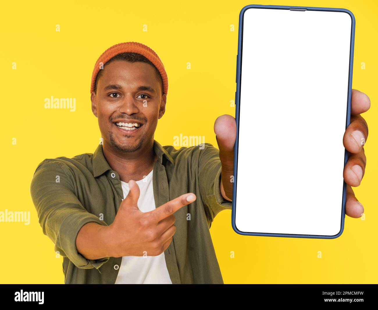 Sorridente studente africano posa con un grande telefono cellulare con schermo bianco, su sfondo giallo con spazio copia. Questa immagine è perfetta per il posizionamento dei prodotti o per i concetti pubblicitari. Foto di alta qualità Foto Stock