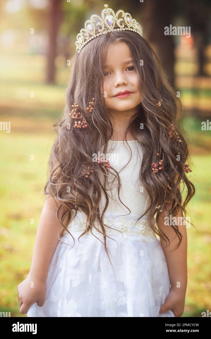 Bambina in vestito bianco e principessa corona, si pone per la fotocamera  con un bel look, spazio copia, tema giorno per i bambini Foto stock - Alamy