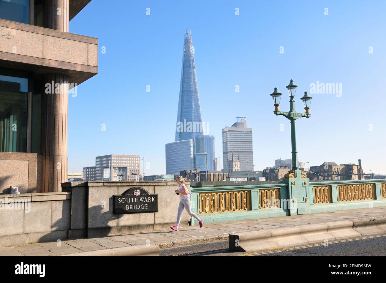 Giovane donna che fa jogging sul Southwark Bridge sul Tamigi con l'edificio Shard sullo sfondo. Londra, Inghilterra, Regno Unito. città, pareggiatore, esercizio fisico, jogging Foto Stock