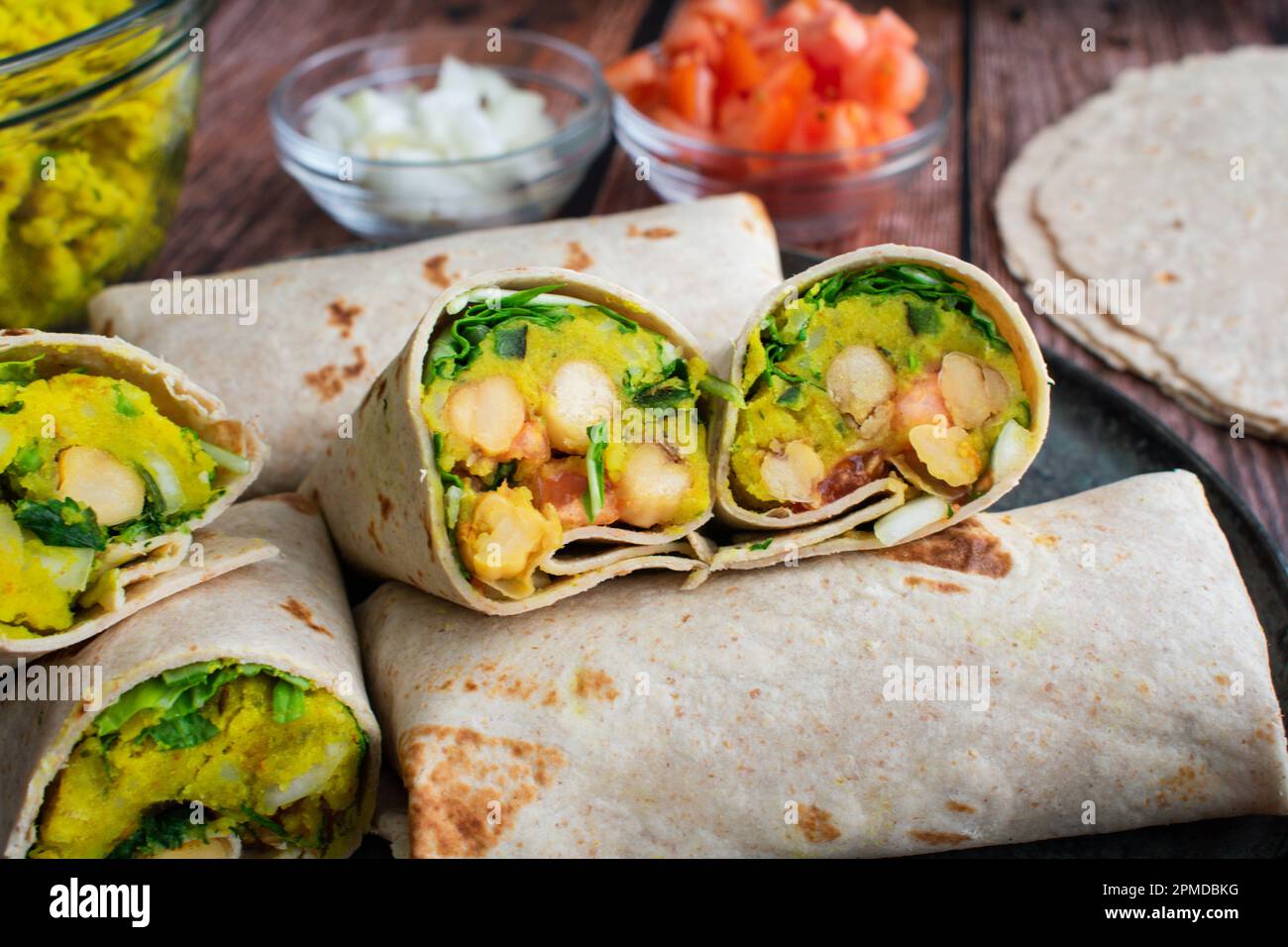 Involtini di samosa - patate speziate Ceci burritos di chutney: Involtini interi e tagliati a metà fatti con ingredienti di samosa indiana e ceci speziati Foto Stock