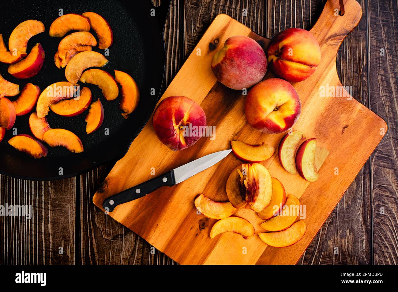 Pesche fresche tagliate a fette su un tagliere di legno: Pesche non pelate tagliate a fette sottili con un coltello da parare Foto Stock