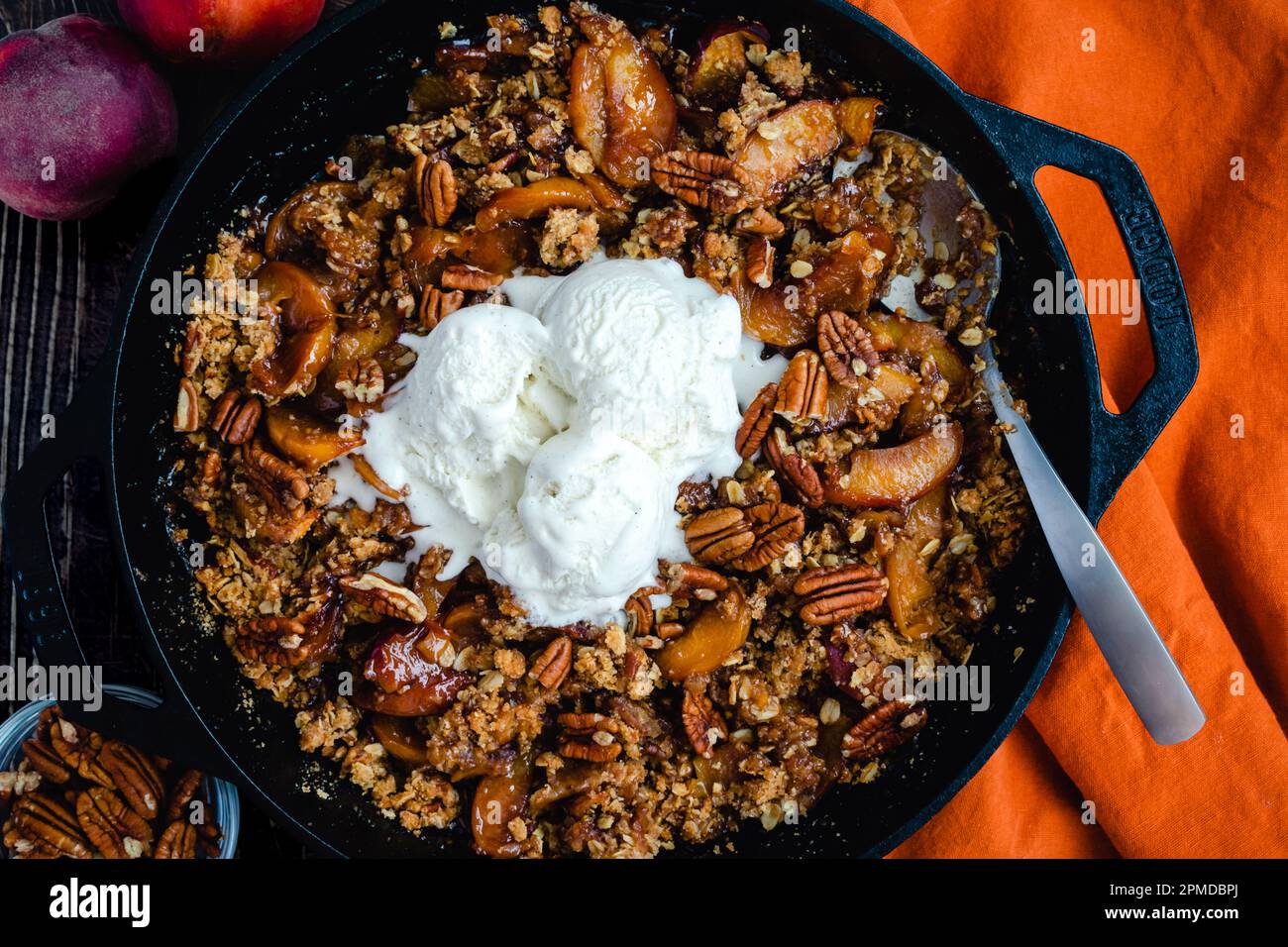 Peach Pecan Bourbon croccante con gelato alla vaniglia: Dessert a base di pesche, bourbon e noci pecan in una padella di ghisa Foto Stock