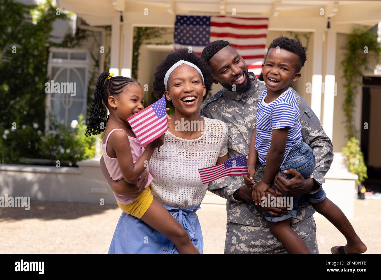 Soldato africano americano marito e madre che trasportano bambini con bandiere d'america fuori casa Foto Stock