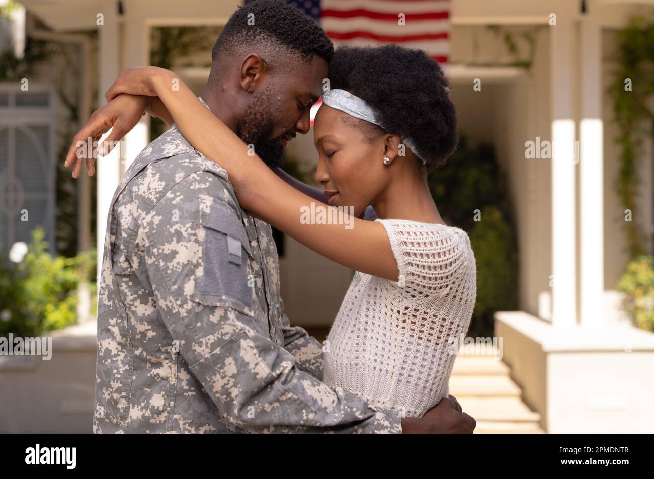 Vista laterale del marito e della moglie del soldato dell'esercito afro-americano con testa a testa in piedi fuori casa Foto Stock