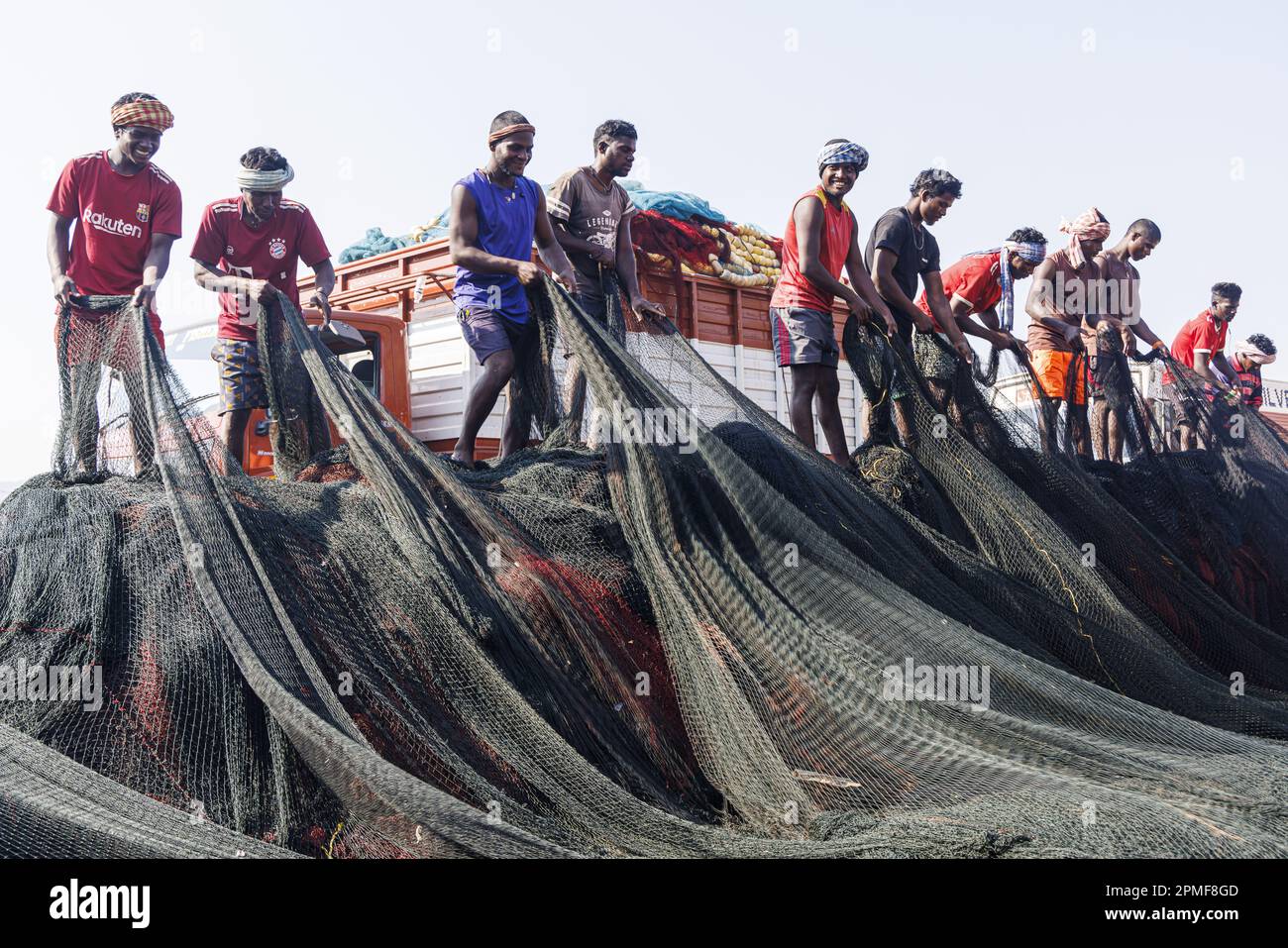 India, Goa, Panaji, porto di pesca, pescatori che ripiegano una rete Foto Stock