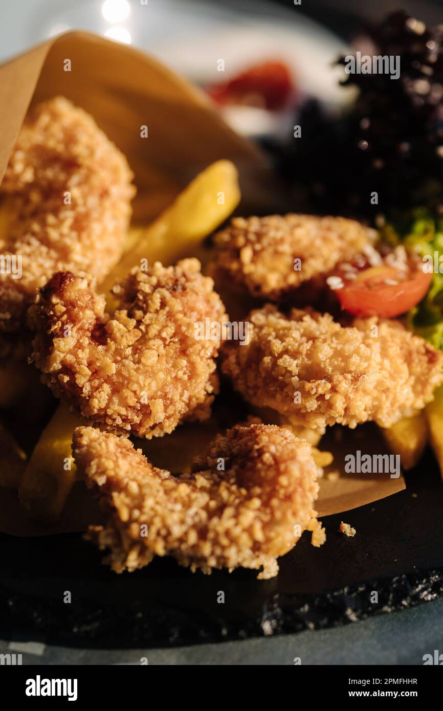 Gamberetti fritti in pangrattato serviti in carta alimentare su piatto Foto Stock