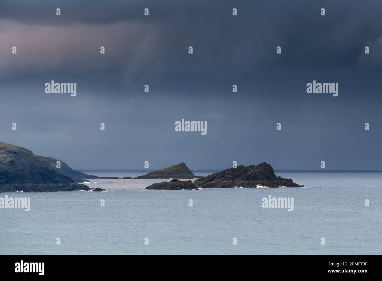 Mare calmo intorno alle due isole rocciose l'oca e il Chick Off Pentire Point East headland a Fistral Bay in Cornovaglia nel Regno Unito. Foto Stock