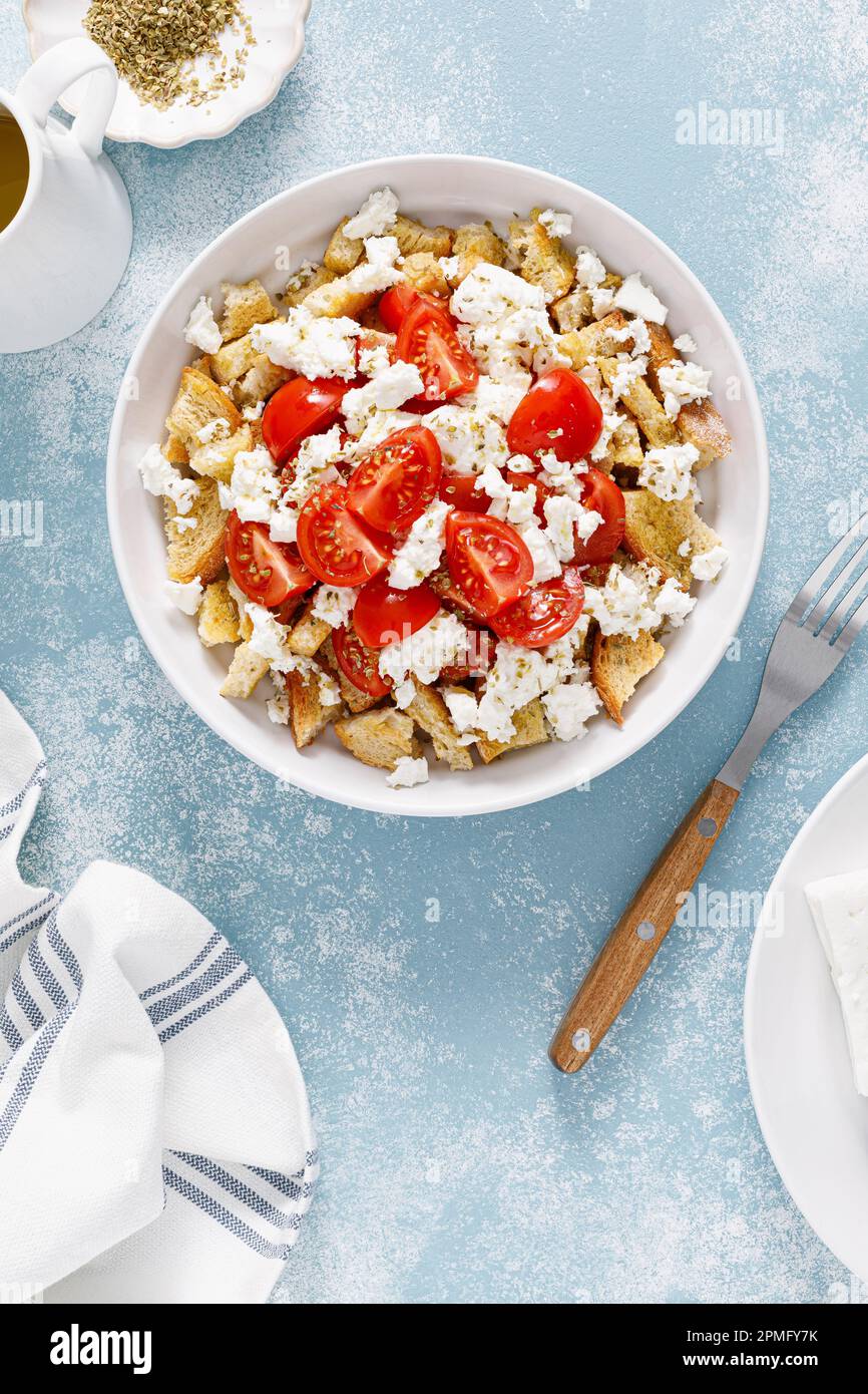 Dakos o insalata di koukouvagia. Ricetta classica insalata di fette biscottate di orzo cretese con pomodoro fresco, mizithra e origano. Tradizionale greco mediterraneo cu Foto Stock