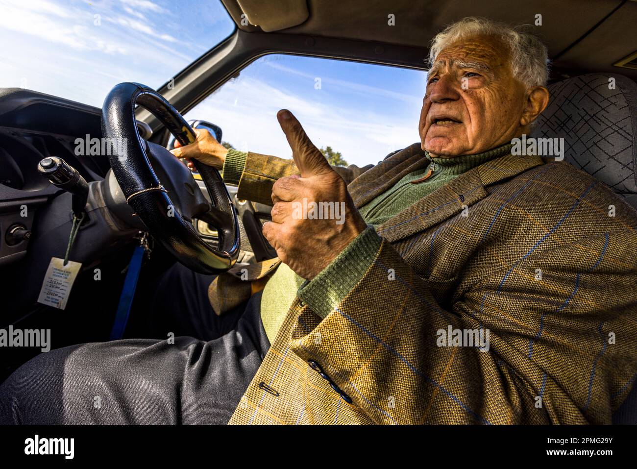 Antonis Hadji Roussos fa un gesto con il pollice alzato mentre parla da dietro il volante della sua auto a Kormakitis (Korucam), Repubblica Turca di Cipro del Nord (RTNC). Foto Stock