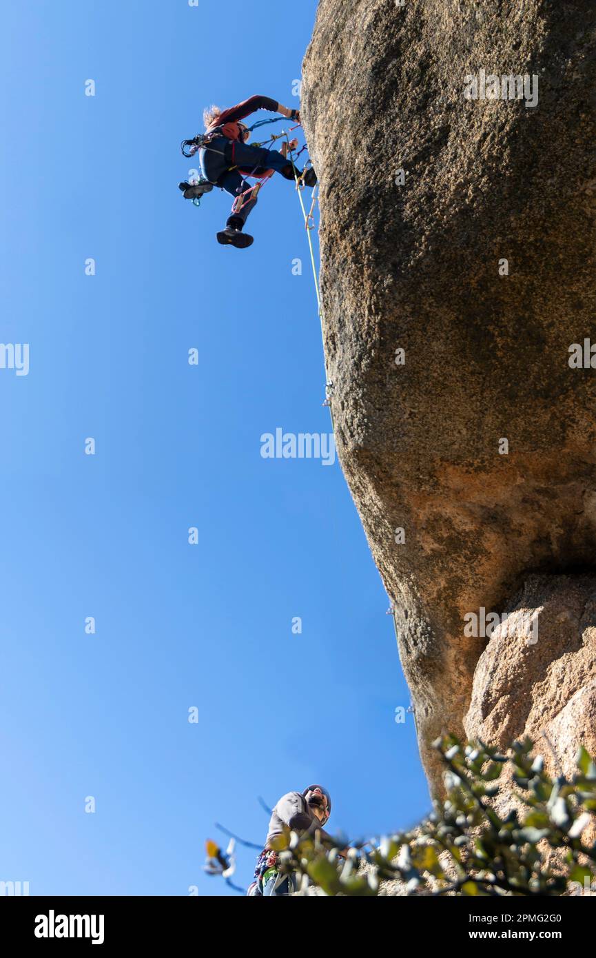 due giovani adulti che lavorano insieme per scalare una parete di granito. Arrampicata su roccia. Concetto di sport estremi Foto Stock