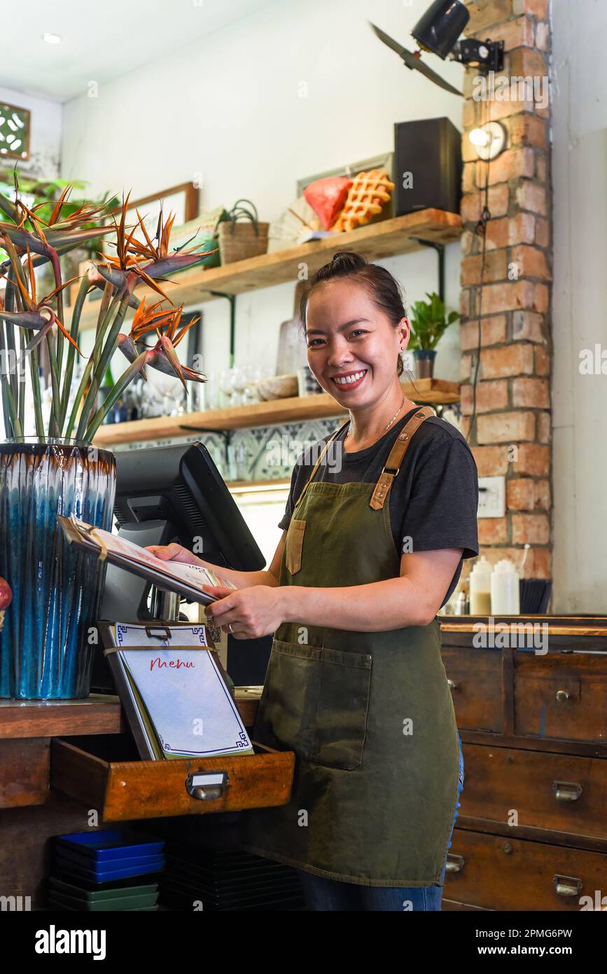 Cameriera felice vietnamita che lavora in una cucina di un caffè Foto Stock