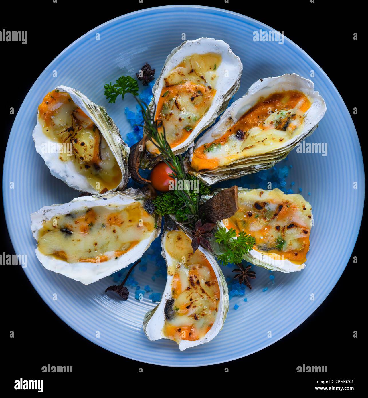 ostriche cotte con formaggio su piatto con sale blu isolato sulla vista superiore nera Foto Stock