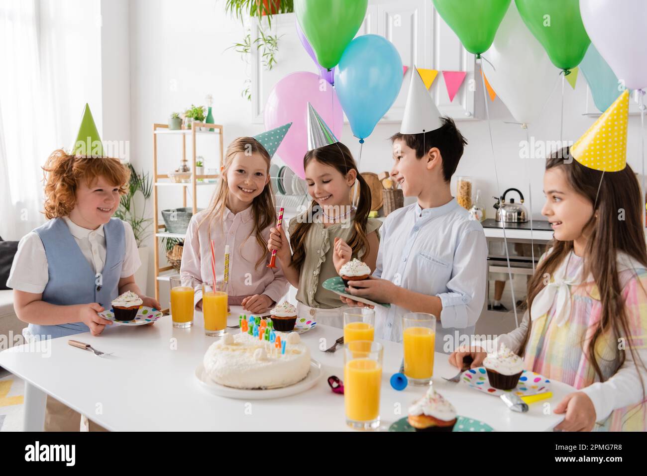 gruppo di bambini gioiosi in cappellini festa divertirsi durante la festa  di compleanno accanto a palloncini colorati, immagine stock Foto stock -  Alamy