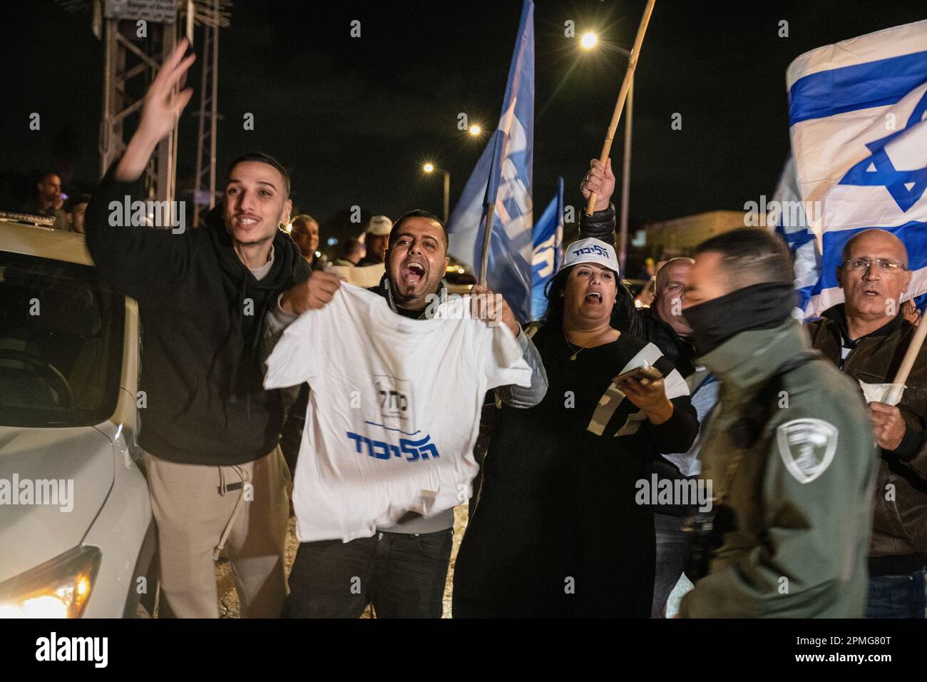 Hadera, Israele. 12th Apr, 2023. I manifestanti di destra tengono le camicie del partito di Likud mentre cantano e fanno un gesto contro i manifestanti anti anti anti-riforma durante la manifestazione. I manifestanti pro e anti della riforma giudiziaria ad Hadera, dimostrano al di fuori di una cerimonia Mimouna in partecipazione del primo ministro Benjamin Netanyahu, si sono verificati scontri tra i manifestanti anti anti anti anti-riforma e gli attivisti di destra favorevoli alla riforma. Credit: SOPA Images Limited/Alamy Live News Foto Stock