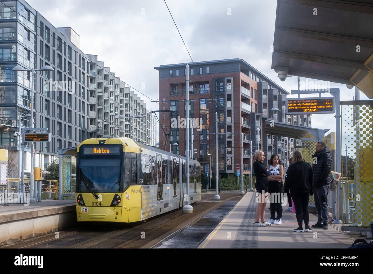 2023 aprile - Manchester tram per Ashton chiamata a una stazione con i passeggeri sul plateau Foto Stock