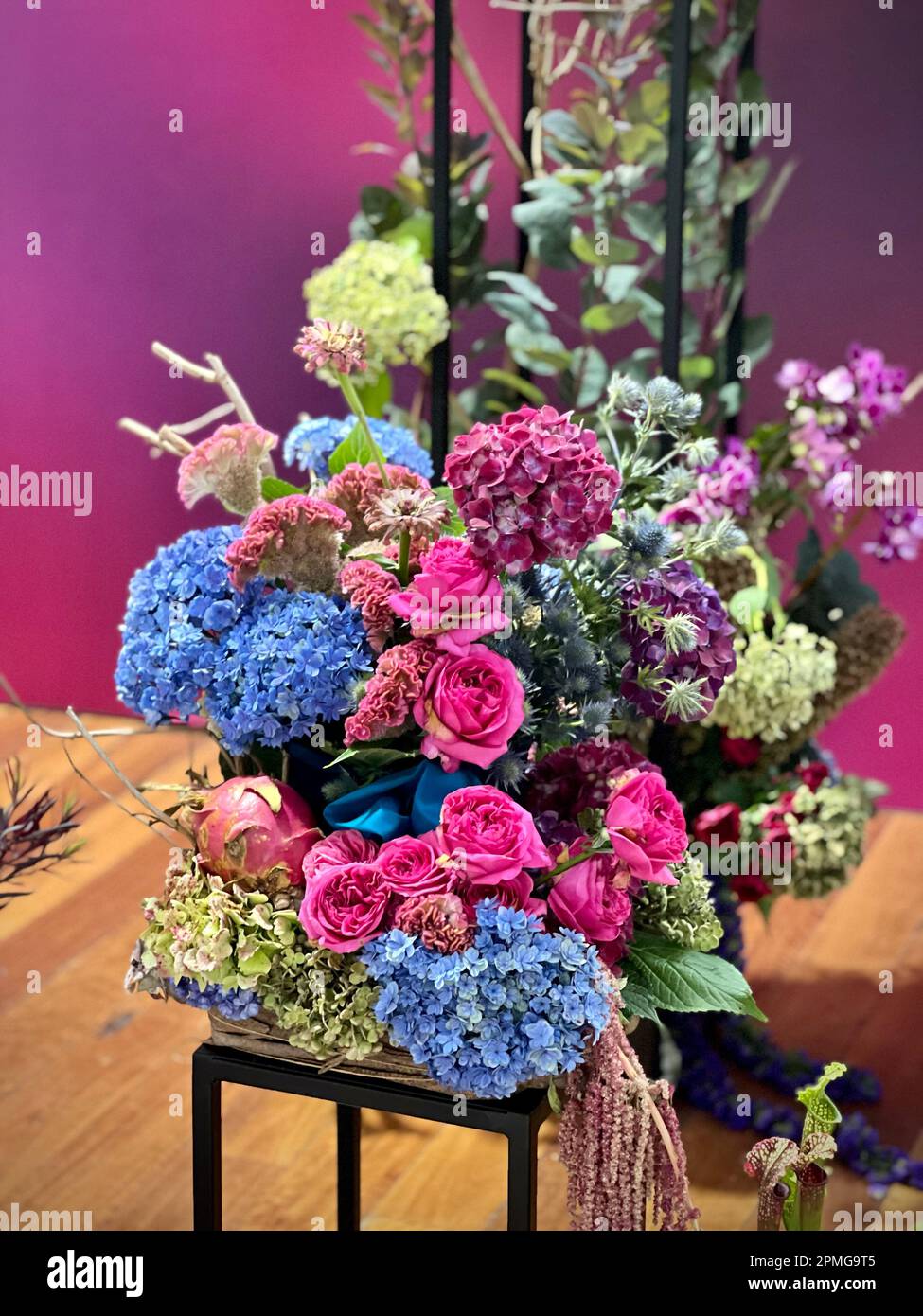 Una vivace esposizione di fiori disposti in un supporto decorativo in filo di ferro su un tavolo, fornendo un allegro punto focale per qualsiasi stanza Foto Stock