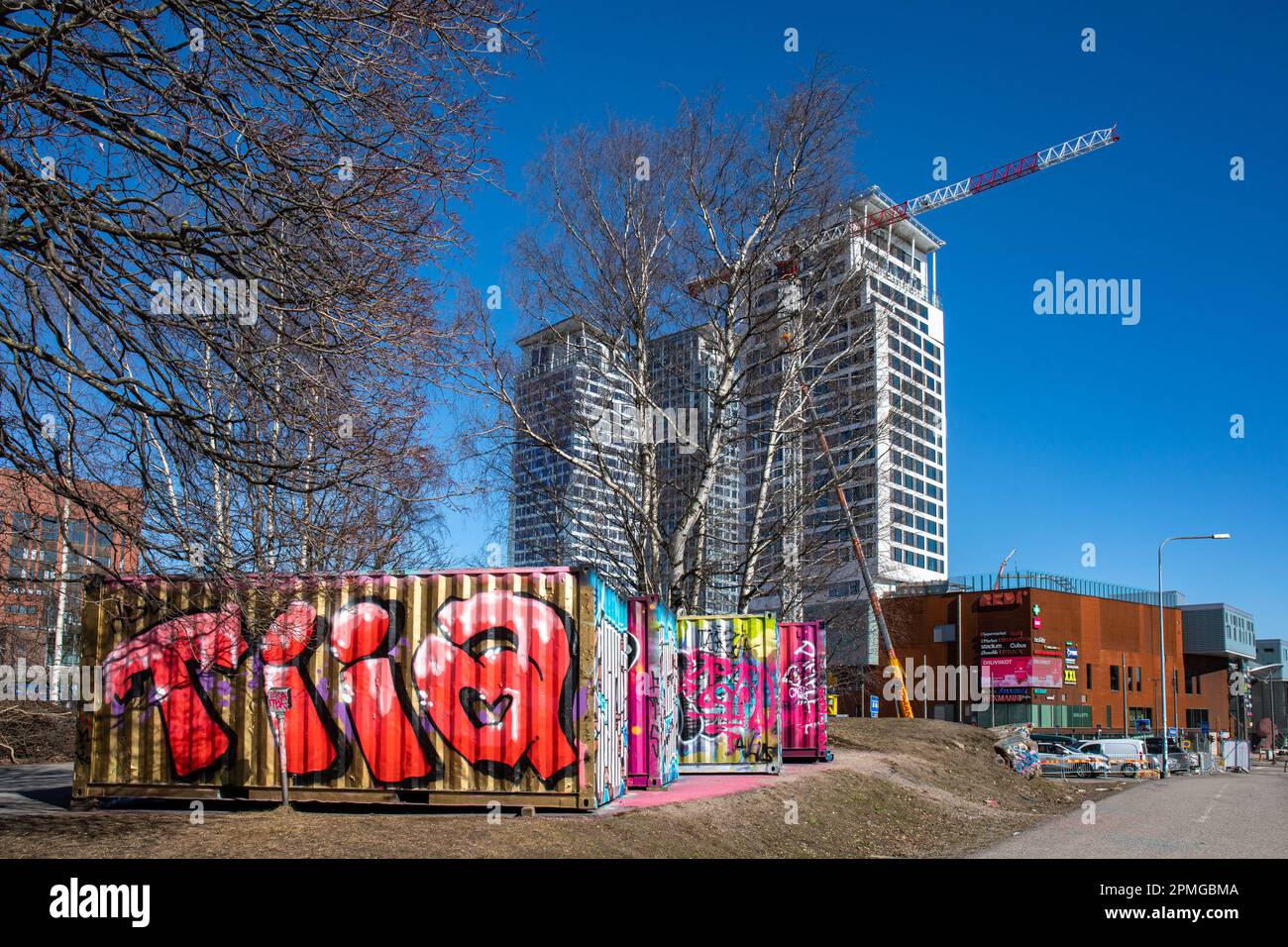 Graffiti ha coperto i contenitori di trasporto davanti, Kalasatama alti edifici sullo sfondo, nel distretto di Suvilahti di Helsinki, Finlandia Foto Stock