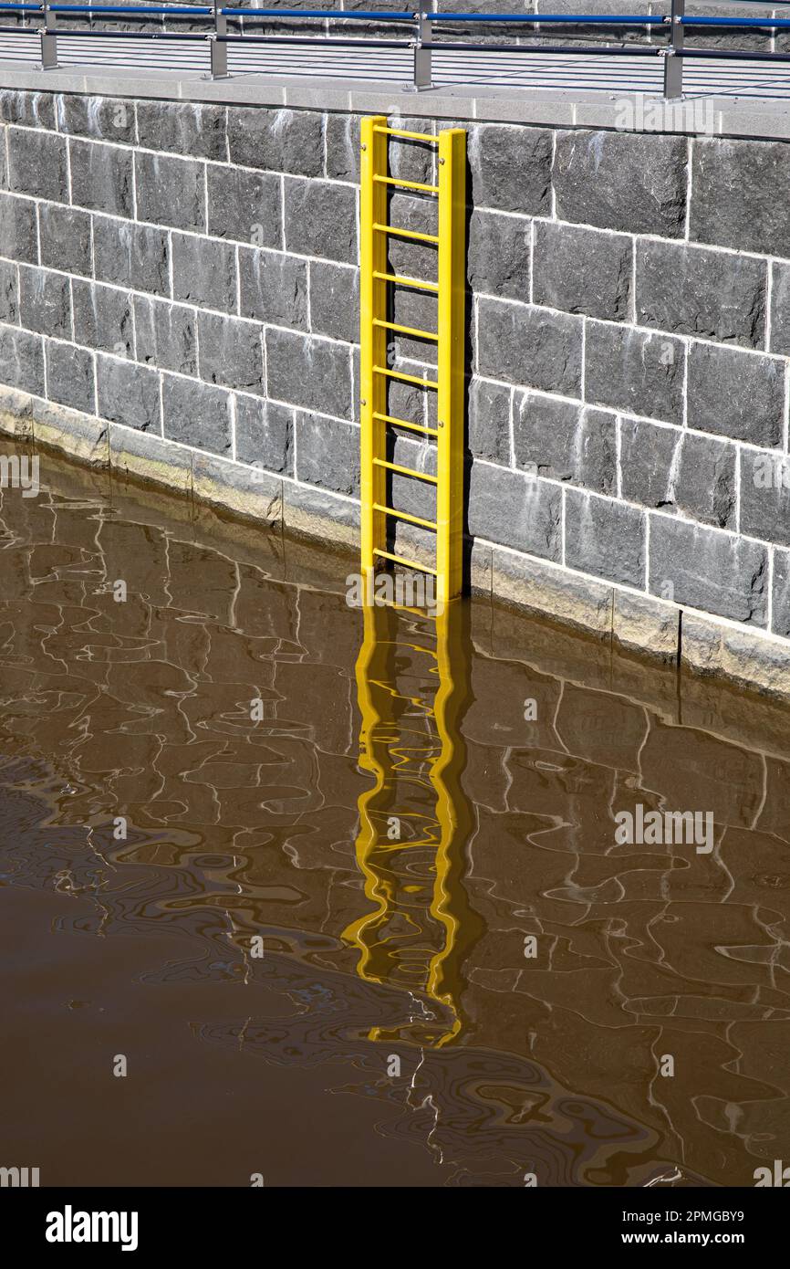 Scala di salvataggio gialla sospesa sulla sponda del canale nel distretto Sompasaari di Helsinki, Finlandia Foto Stock