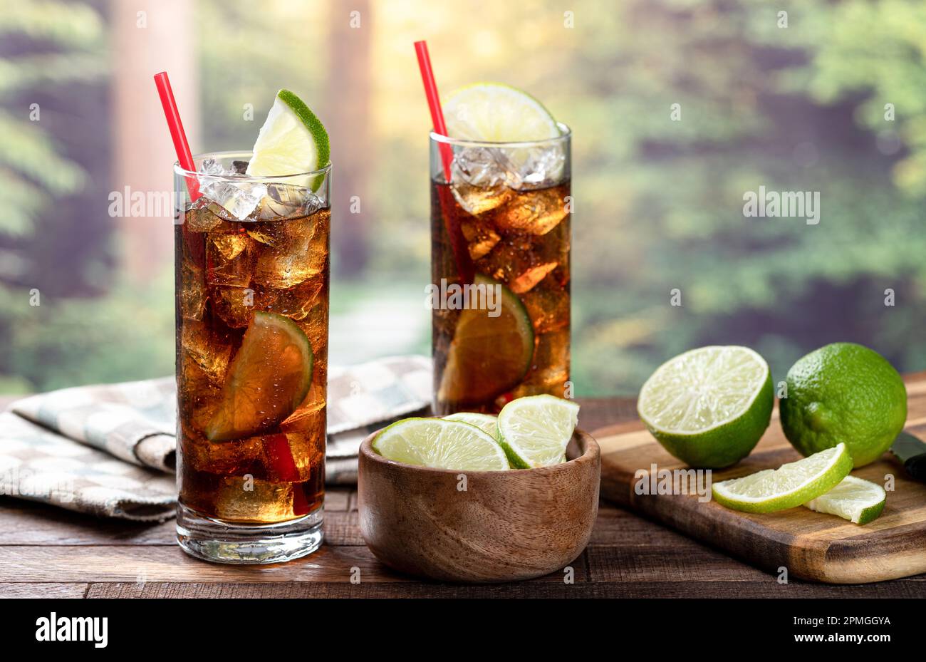 Cocktail al rum e alla cola con fettina di lime su un tavolo rustico in legno con sfondo estivo e spazio copia Foto Stock