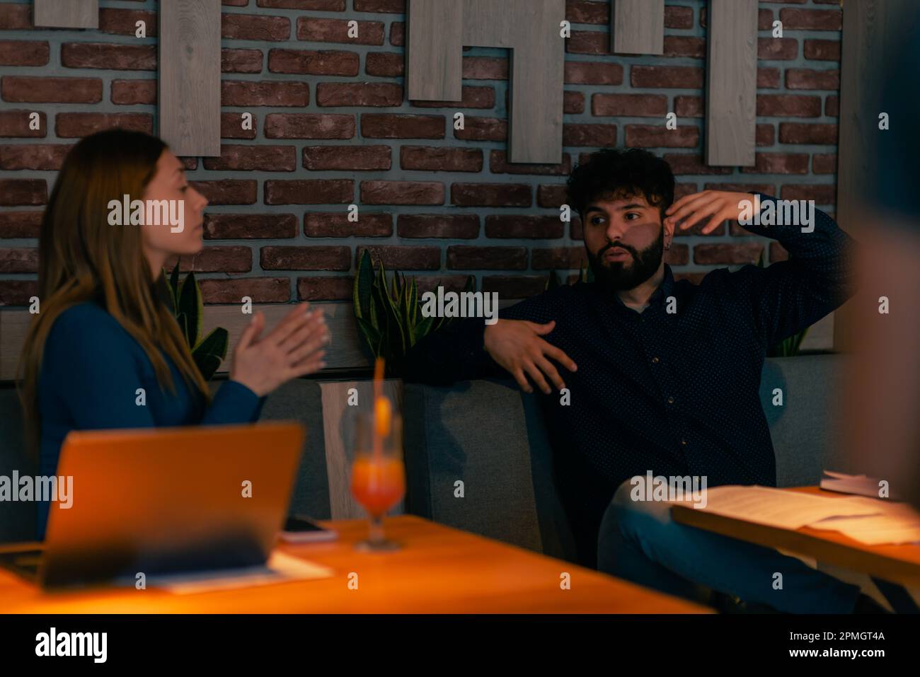 Coppia simpatica seduta insieme al caffè, sorridendo parlando e facendo una discussione su qualcosa, spiegando le mani di spirito Foto Stock