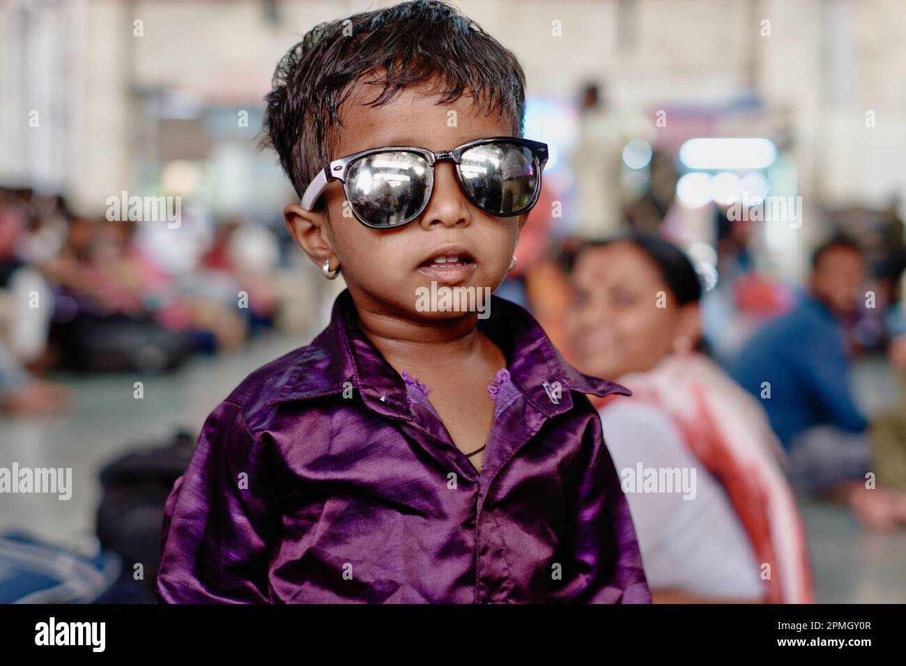 Un ragazzo indiano vestito natamente dell'età dell'asilo che indossa gli occhiali da sole così come gli orecchini, apparentemente styled secondo le linee delle celebrita' di Bollywood Foto Stock