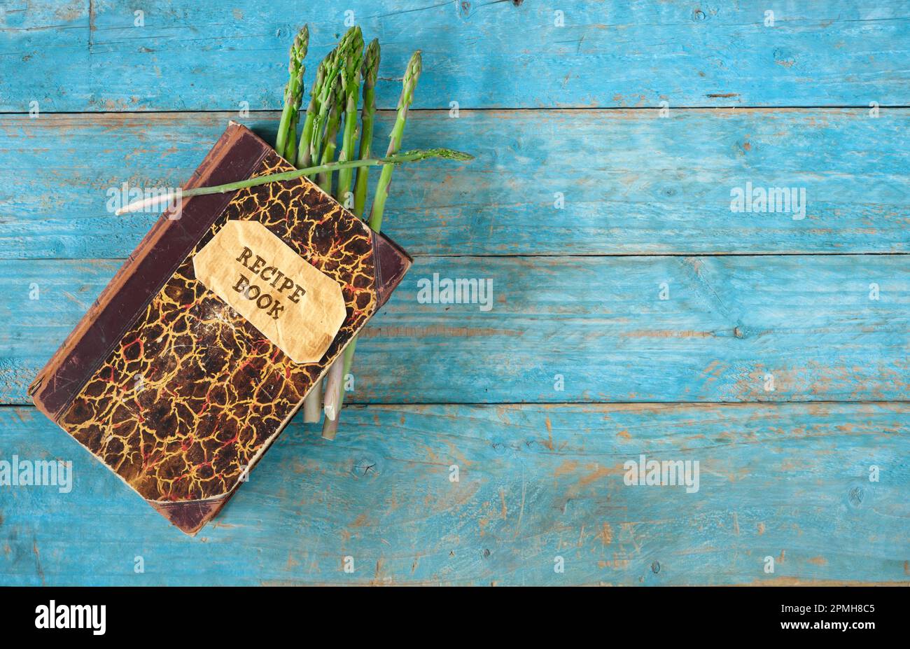 mazzo di asparagi verdi freschi e vecchio ricettario su sfondo di legno, cucina di stagione e concetto di sana alimentazione Foto Stock