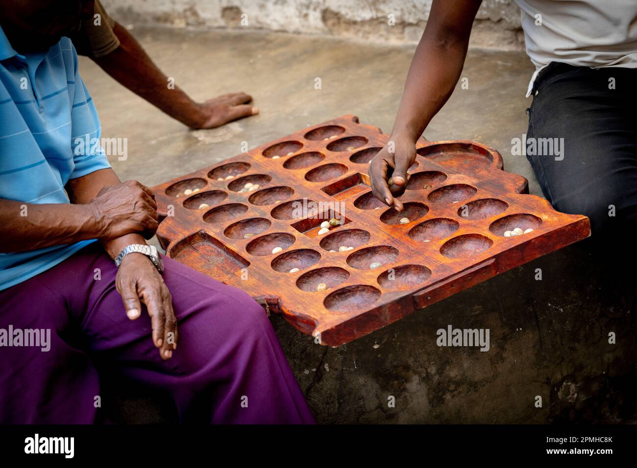 Uomini che giocano il famoso gioco da tavolo Bao in strada, Stone Town, Zanzibar, Tanzania, Africa orientale, Africa Foto Stock