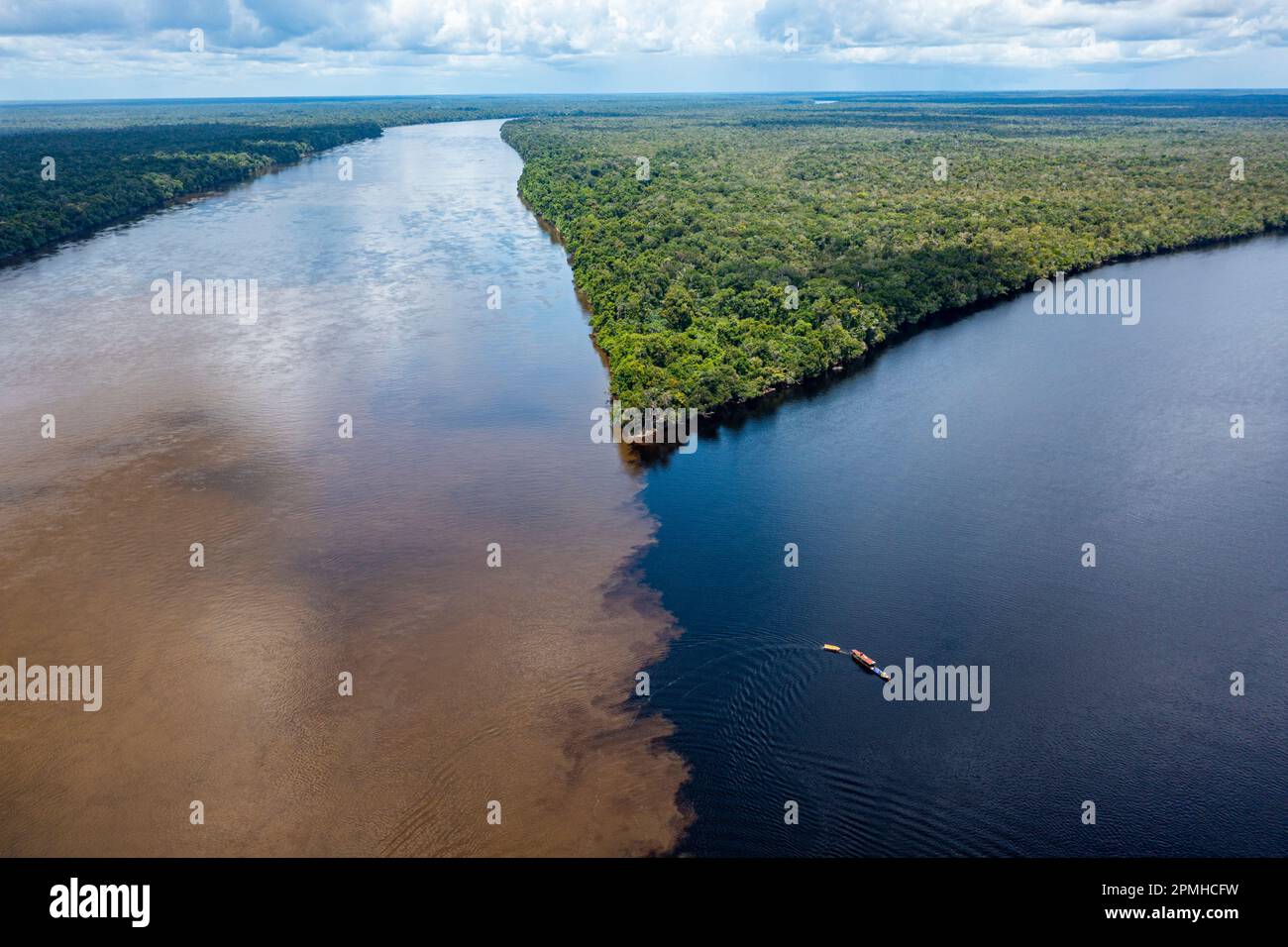 Piccola barca sul punto d'incontro del fiume Casiquiare e del fiume Pasimoni nero, nel profondo sud del Venezuela, Sud America Foto Stock