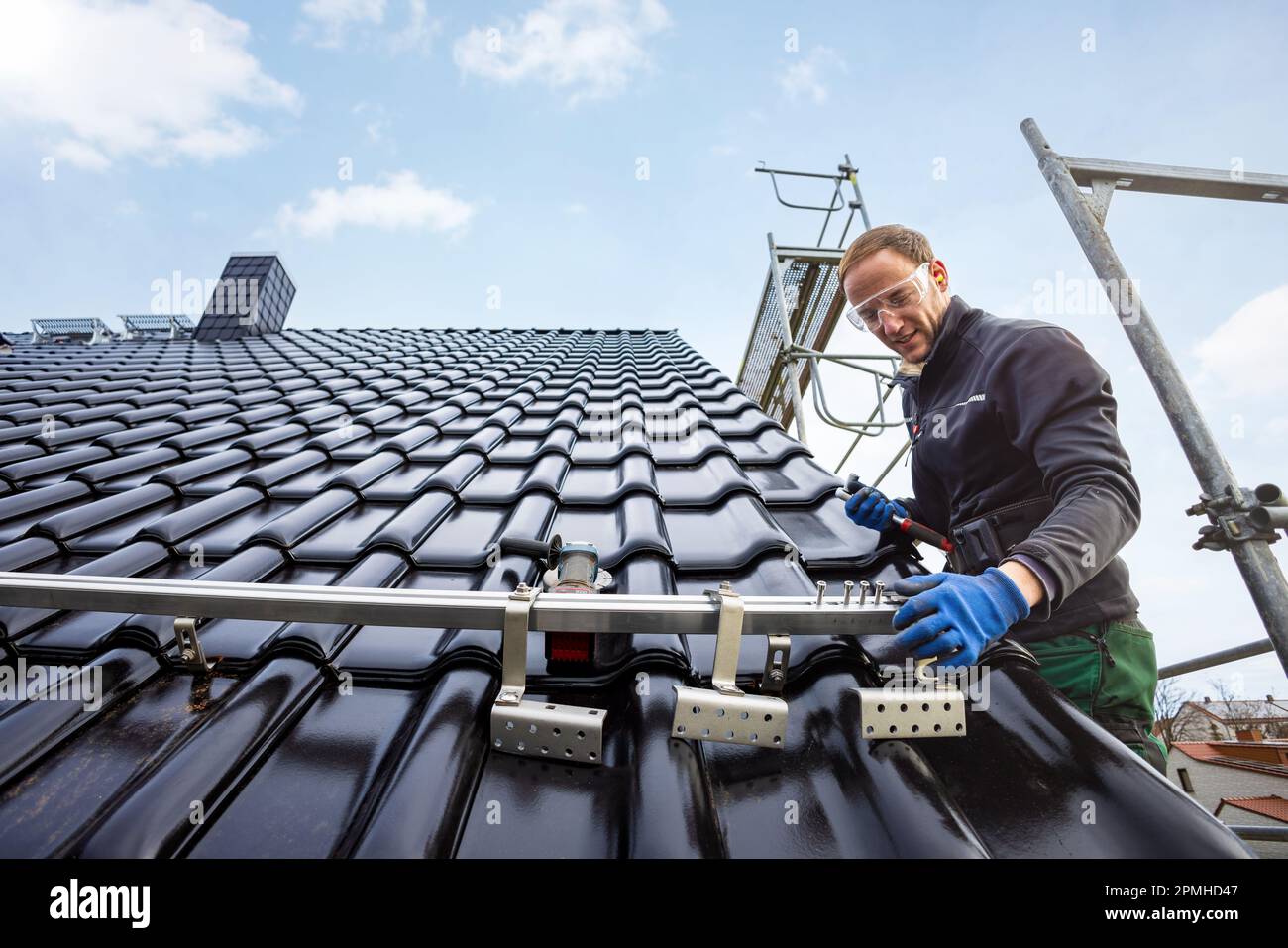 Artigiano che installa il sistema di montaggio del pannello solare su un tetto Foto Stock