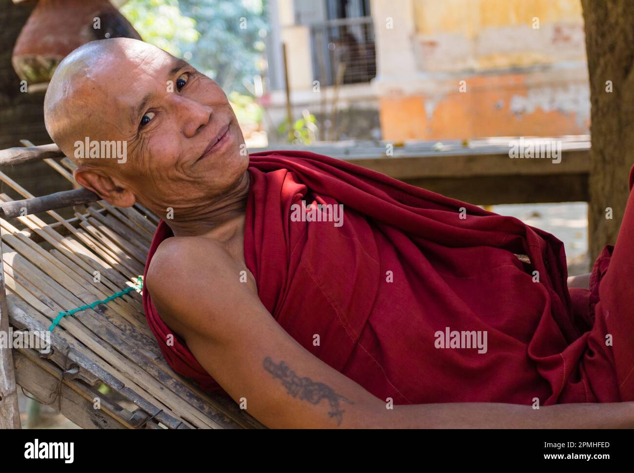 Monaco anziano che riposa su una sedia reclinabile fuori del Tempio di Shwenandaw, Mandalay, Myanmar (Birmania), Asia Foto Stock