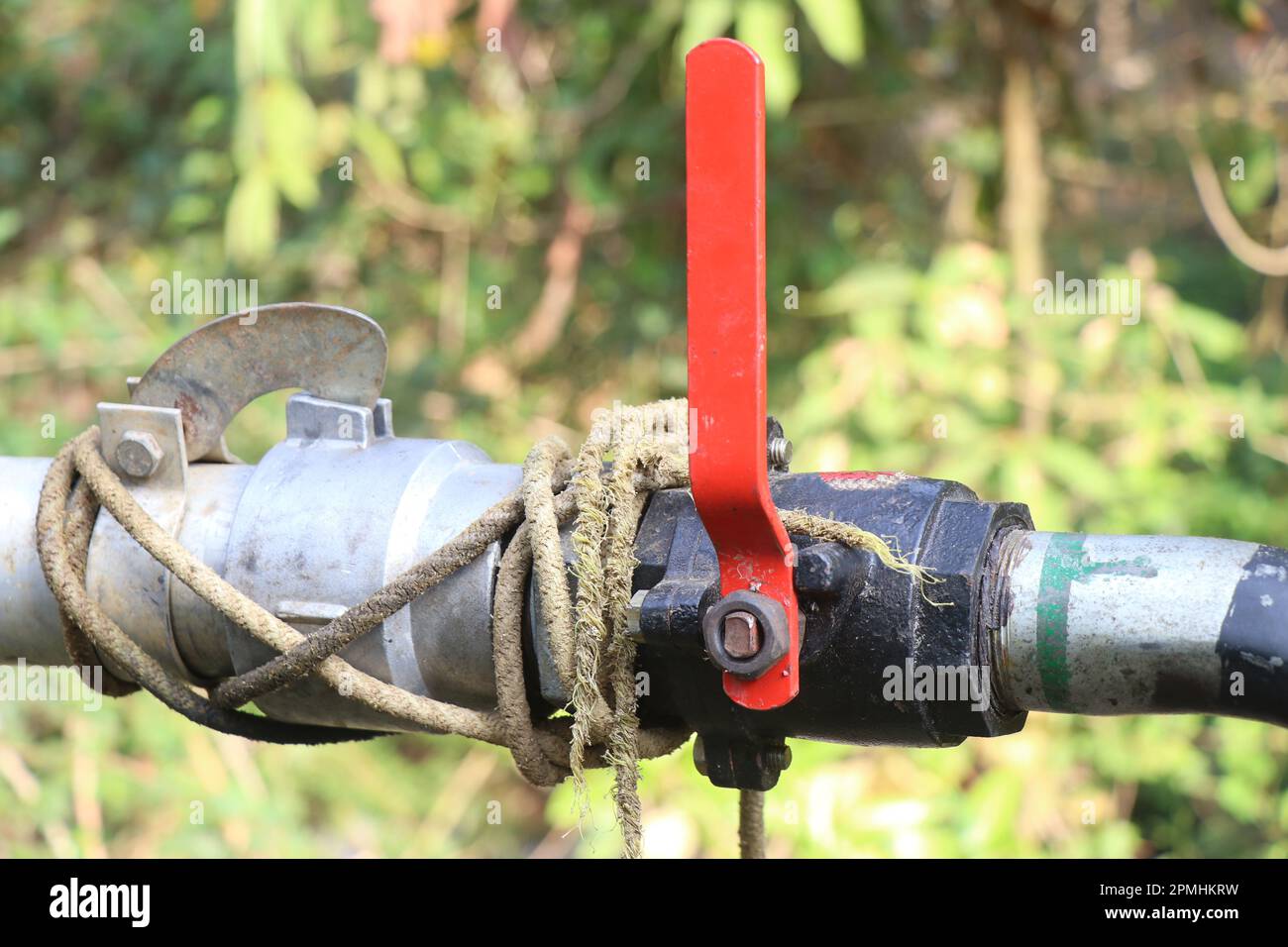 valvola di arresto dell'acqua per impieghi gravosi installata sul tubo di trasporto dell'acqua. Valvola a sfera filettata con impugnatura rossa Foto Stock